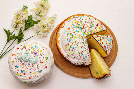 Easter cake on white putty background. Traditional Orthodox festive bread, wooden cutting board, flowers decorの写真素材