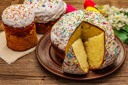 Easter cakes on old wooden table. Traditional Orthodox festive bread, cut pieces, artificial decor