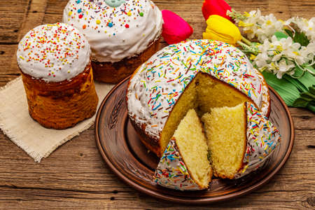 Easter cakes on old wooden table. Traditional Orthodox festive bread, cut pieces, artificial decorの写真素材