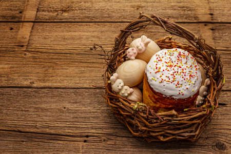 Easter cake, rabbits and eggs in wicker basket. Traditional Orthodox festive bread, vintage wooden boards backgroundの写真素材