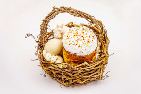 Easter cake, rabbits and eggs in wicker basket isolated on white background. Traditional Orthodox festive breadの写真素材