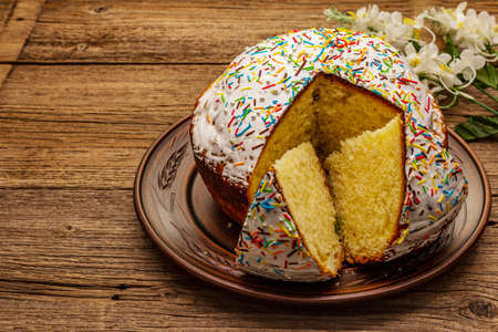 Easter cake on old wooden table. Traditional Orthodox festive bread, cut pieces, artificial decorの写真素材