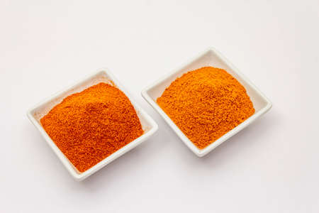 Two types of Hungarian paprika powder, hot and sweet, isolated on white background. Traditional seasoning in ceramic plateの写真素材