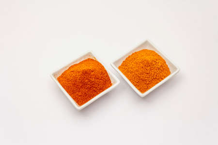 Two types of Hungarian paprika powder, hot and sweet, isolated on white background. Traditional seasoning in ceramic plateの写真素材