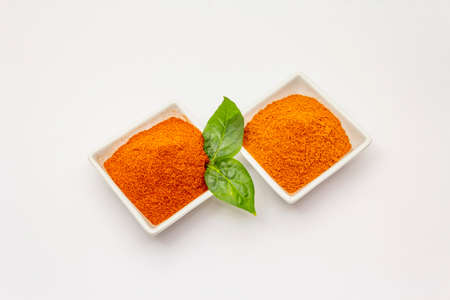 Two types of Hungarian paprika powder, hot and sweet, isolated on white background. Traditional seasoning in ceramic plateの写真素材