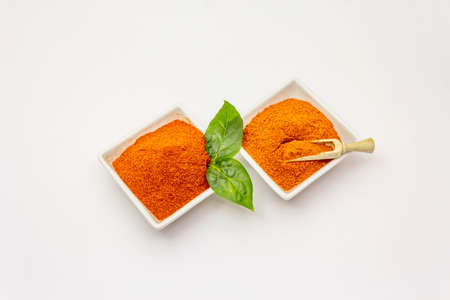Two types of Hungarian paprika powder, hot and sweet, isolated on white background. Traditional seasoning in ceramic plateの写真素材