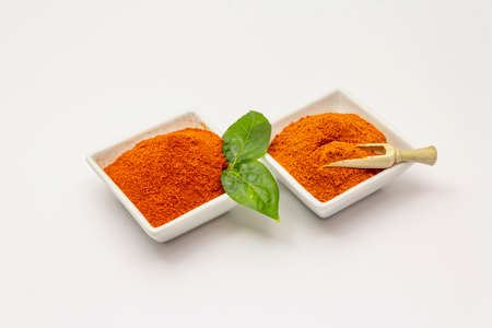 Two types of Hungarian paprika powder, hot and sweet, isolated on white background. Traditional seasoning in ceramic plateの写真素材