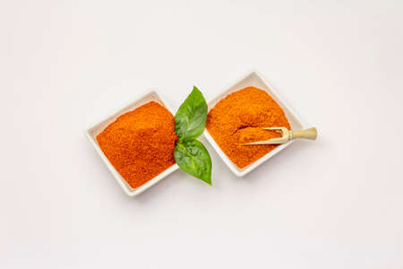Two types of Hungarian paprika powder, hot and sweet, isolated on white background. Traditional seasoning in ceramic plateの写真素材
