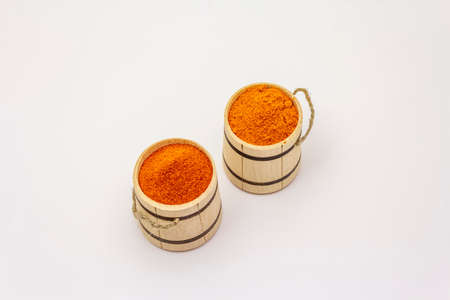 Two types of Hungarian paprika powder, hot and sweet, isolated on white background. Traditional seasoning in wooden barrelの写真素材