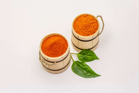 Two types of Hungarian paprika powder, hot and sweet, isolated on white background. Traditional seasoning in wooden barrelの写真素材