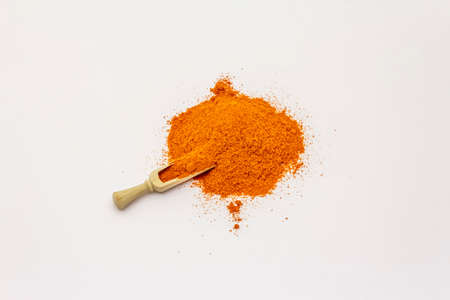 Hungarian hot paprika powder isolated on white background. Heap of traditional seasoning, wooden scoopの写真素材