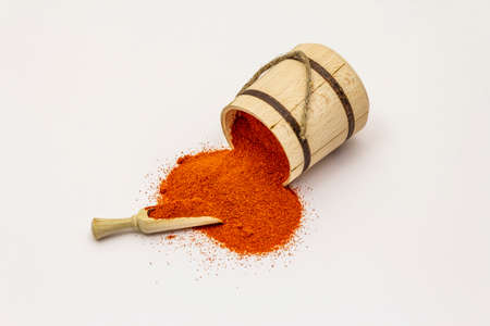 Hungarian sweet paprika powder isolated on white background. Traditional seasoning in wooden barrelの写真素材