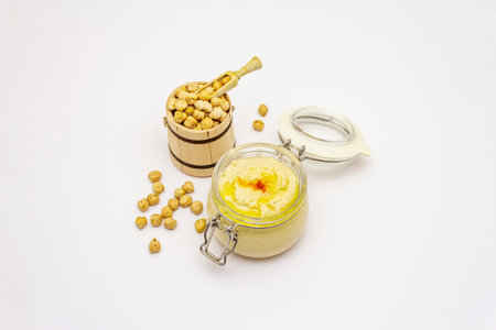 Hummus isolated on white background. Dry chickpea in wooden barrel. Traditional food in Middle...