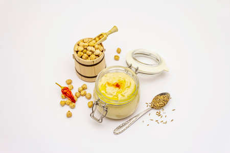 Hummus isolated on white background. Dry chickpea in wooden barrel, cumin and chili pepper. Traditional food in Middle Eastern and Mediterranean cuisineの写真素材
