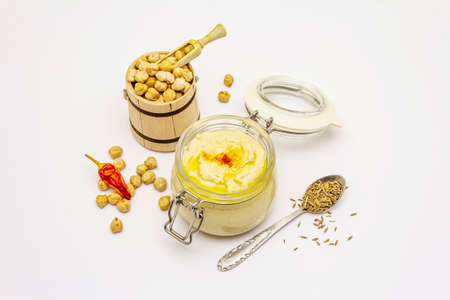 Hummus isolated on white background. Dry chickpea in wooden barrel, cumin and chili pepper. Traditional food in Middle Eastern and Mediterranean cuisineの写真素材