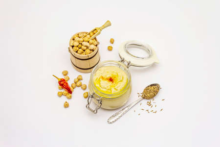 Hummus isolated on white background. Dry chickpea in wooden barrel, cumin and chili pepper. Traditional food in Middle Eastern and Mediterranean cuisineの写真素材