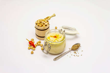 Hummus isolated on white background. Dry chickpea in wooden barrel, cumin and chili pepper. Traditional food in Middle Eastern and Mediterranean cuisineの写真素材