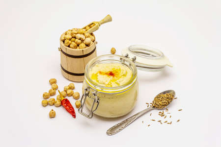 Hummus isolated on white background. Dry chickpea in wooden barrel, cumin and chili pepper. Traditional food in Middle Eastern and Mediterranean cuisineの写真素材