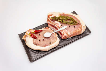 Raw pork steaks isolated on white background. Spices, sea salt, rosemary, chili pepperの写真素材