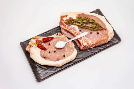 Raw pork steaks isolated on white background. Spices, sea salt, rosemary, chili pepperの写真素材