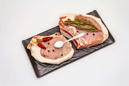 Raw pork steaks isolated on white background. Spices, sea salt, rosemary, chili pepperの写真素材