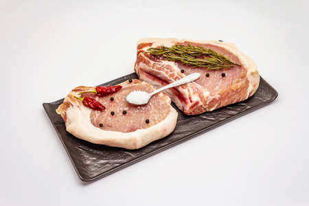 Raw pork steaks isolated on white background. Spices, sea salt, rosemary, chili pepperの写真素材