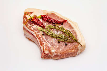 Raw pork steak isolated on white background. Spices, sea salt, rosemary, chili pepperの写真素材