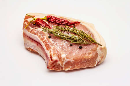 Raw pork steak isolated on white background. Spices, sea salt, rosemary, chili pepperの写真素材