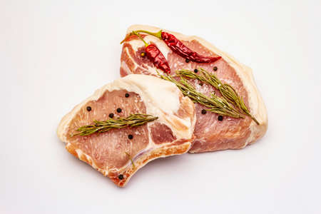 Raw pork steaks isolated on white background. Spices, sea salt, rosemary, chili pepperの写真素材