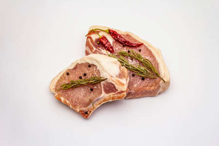 Raw pork steaks isolated on white background. Spices, sea salt, rosemary, chili pepperの写真素材