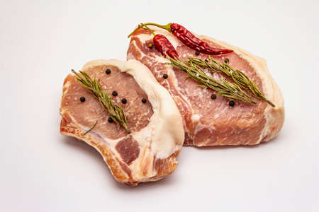 Raw pork steaks isolated on white background. Spices, sea salt, rosemary, chili pepperの写真素材