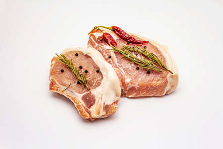 Raw pork steaks isolated on white background. Spices, sea salt, rosemary, chili pepperの写真素材