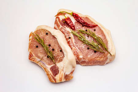 Raw pork steaks isolated on white background. Spices, sea salt, rosemary, chili pepperの写真素材