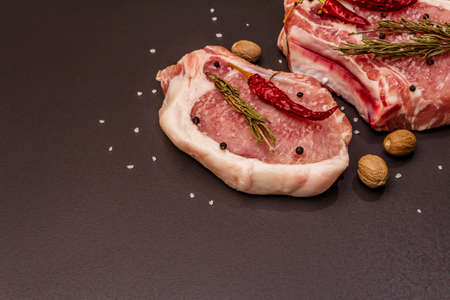 Raw pork steaks on trendy black stone concrete background. Spices, sea salt, rosemary, chili pepperの写真素材