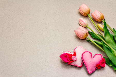 Greetings card, wallpaper, backdrop. Happy Mothers Day, St.Valentines or Wedding. Gentle pink tulips, handmade felt hearts. Stone concrete backgroundの写真素材