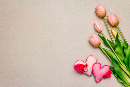 Greetings card, wallpaper, backdrop. Happy Mothers Day, St.Valentines or Wedding. Gentle pink tulips, handmade felt hearts. Stone concrete backgroundの写真素材