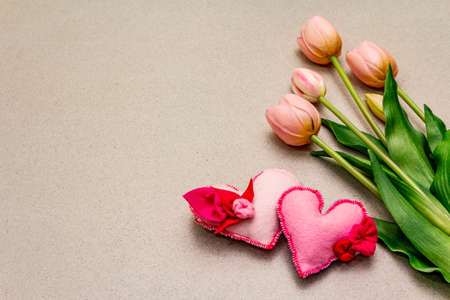 Greetings card, wallpaper, backdrop. Happy Mothers Day, St.Valentines or Wedding. Gentle pink tulips, handmade felt hearts. Stone concrete backgroundの写真素材