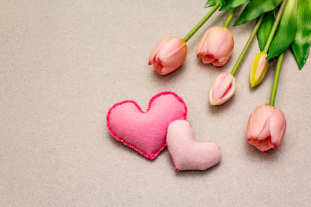 Greetings card, wallpaper, backdrop. Happy Mothers Day, St.Valentines or Wedding. Gentle pink tulips, handmade felt hearts. Stone concrete backgroundの写真素材