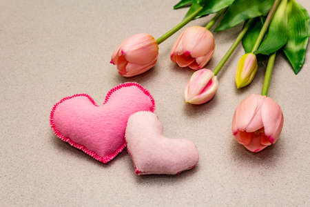 Greetings card, wallpaper, backdrop. Happy Mothers Day, St.Valentines or Wedding. Gentle pink tulips, handmade felt hearts. Stone concrete backgroundの写真素材