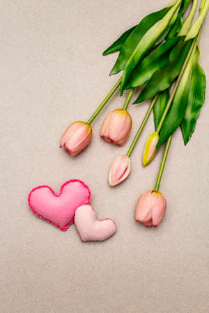Greetings card, wallpaper, backdrop. Happy Mothers Day, St.Valentines or Wedding. Gentle pink tulips, handmade felt hearts. Stone concrete backgroundの写真素材