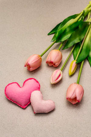 Greetings card, wallpaper, backdrop. Happy Mothers Day, St.Valentines or Wedding. Gentle pink tulips, handmade felt hearts. Stone concrete backgroundの写真素材