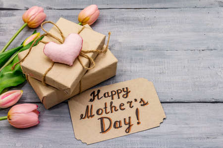 Greetings card for Happy Mothers Day. Gentle pink tulips, handmade felt heart, zero waste packaging gift. Wooden boards backgroundの写真素材
