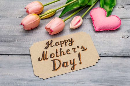 Greetings card for Happy Mothers Day. Gentle pink tulips, handmade felt heart, zero waste packaging gift. Wooden boards backgroundの写真素材