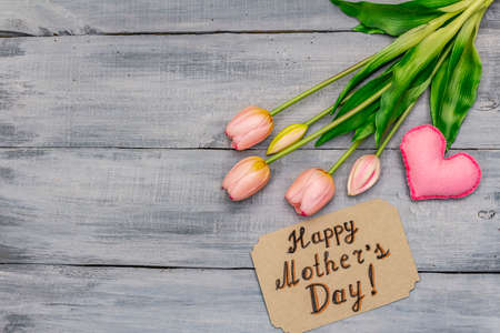 Greetings card for Happy Mothers Day. Gentle pink tulips, handmade felt heart, zero waste packaging gift. Wooden boards backgroundの写真素材