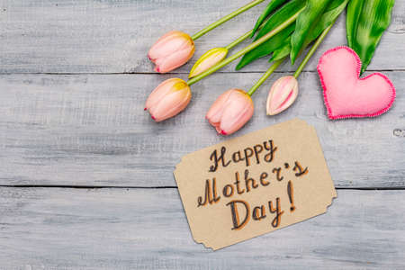 Greetings card for Happy Mothers Day. Gentle pink tulips, handmade felt heart, zero waste packaging gift. Wooden boards backgroundの写真素材