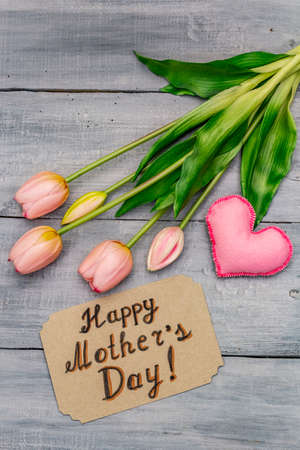 Greetings card for Happy Mothers Day. Gentle pink tulips, handmade felt heart, zero waste packaging gift. Wooden boards backgroundの写真素材