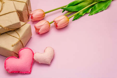 Greetings card, wallpaper, backdrop. Happy Mothers Day, Easter, St.Valentines or Wedding. Gentle pink tulips, handmade felt hearts, zero waste packaging gift on rosy backgroundの写真素材