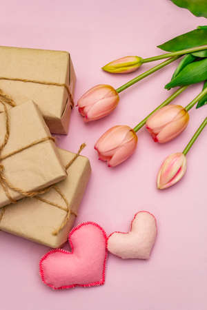 Greetings card, wallpaper, backdrop. Happy Mothers Day, Easter, St.Valentines or Wedding. Gentle pink tulips, handmade felt hearts, zero waste packaging gift on rosy backgroundの写真素材