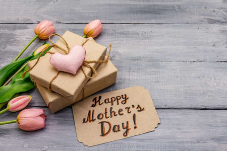 Greetings card for Happy Mothers Day. Gentle pink tulips, handmade felt heart, zero waste packaging gift. Wooden boards backgroundの写真素材