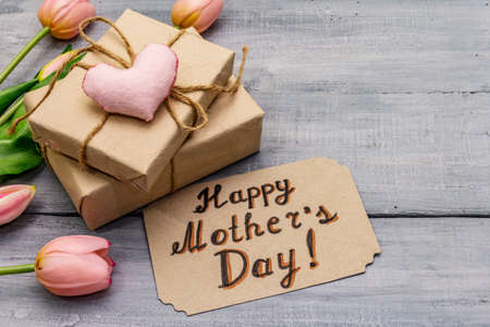 Greetings card for Happy Mothers Day. Gentle pink tulips, handmade felt heart, zero waste packaging gift. Wooden boards backgroundの写真素材